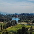 Scenic view of Kodaikanal hill station with mist-covered mountains, lush greenery, and serene lakes.