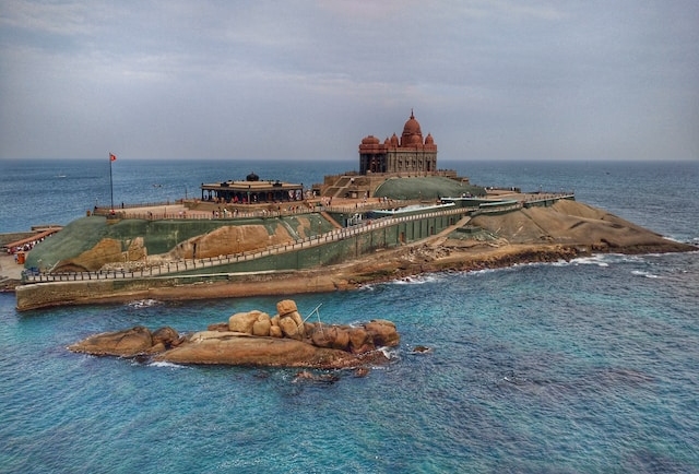 Kanyakumari: Coastal town with colorful boats by the shore, iconic Vivekananda Rock, and breathtaking sunset views.