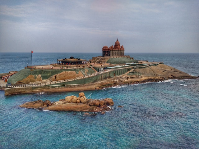 Kanyakumari: Coastal town with colorful boats by the shore, iconic Vivekananda Rock, and breathtaking sunset views.