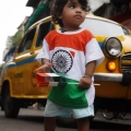 Child proudly wears the Indian national flag and raises the flag of India during a festive celebration.