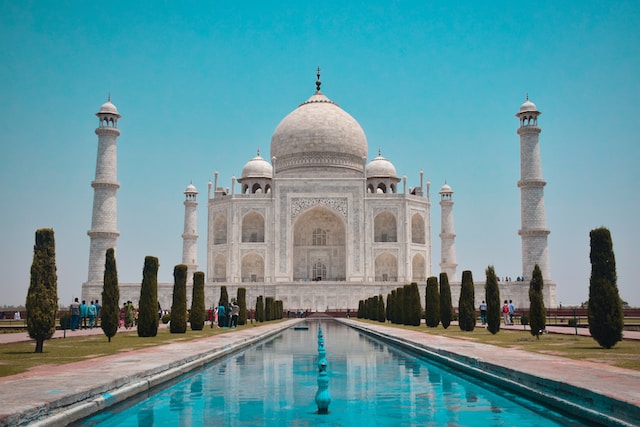 Iconic white marble mausoleum with intricate carvings and reflecting pool in Agra, India.