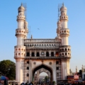 Charminar is a historic monument in Hyderabad, India, with its iconic four minarets rising against a blue sky.