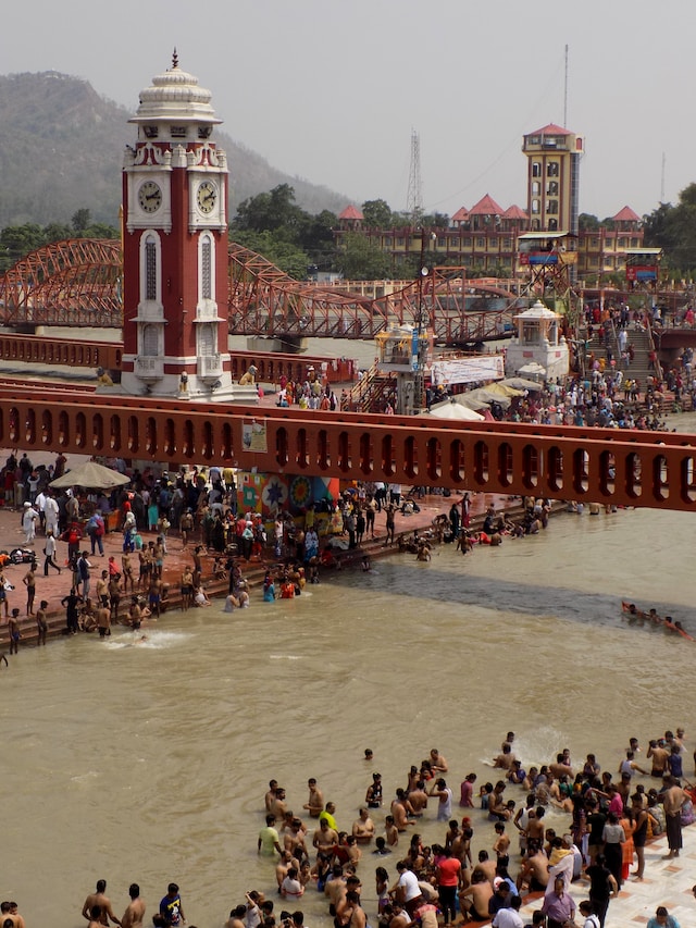 Sacred Ganges River in Haridwar, India, with people participating in a religious ceremony on the ghat