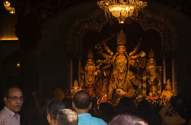 A captivating Durga Puja tableau showcasing the intricate decorations of a pandal, idol of Goddess Durga, and enthusiastic devotees.