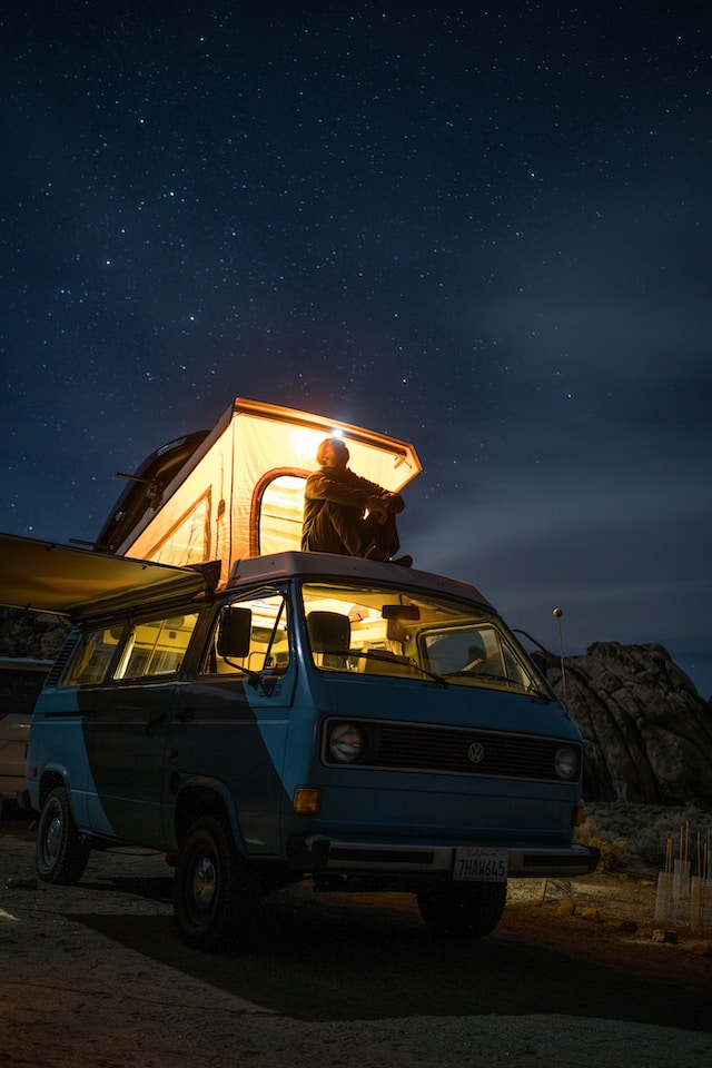 An adventurous traveler with a backpack admiring a stunning evening mountain landscape under a serene and colorful evening sky, evoking the magic of twilight adventures.