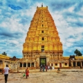 Virupaksha Temple, a majestic stone structure adorned with intricate carvings and towers against a blue sky backdrop.