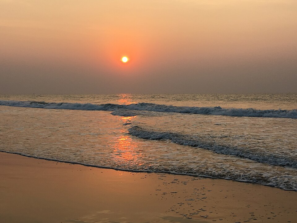 A travel guide titled 'Exploring the Charms of Puri: A Guide to Must-Visit Places' featuring a scenic view of Puri's coastline with clear blue skies, palm trees, and waves gently crashing on the shore.