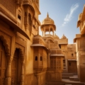 A panoramic view of Jaisalmer, a city in the desert. The golden-hued fort stands tall amidst sand dunes, with intricate architecture and bustling streets. The sun sets, casting a warm, golden glow over the city, evoking a sense of timeless charm and beauty.