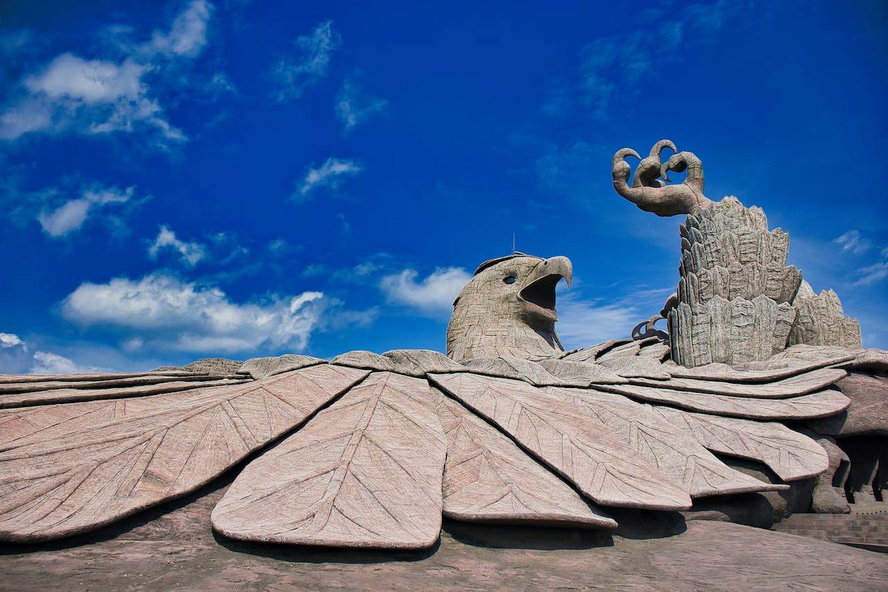 A scenic view of a tourist destination showcasing breathtaking landscapes and a monumental sculpture, inviting visitors to discover the enchanting adventures at Jatayu, a spectacular tourism spot.